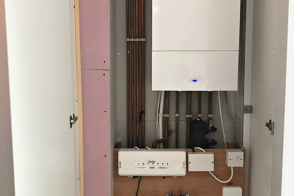 A new boiler in a built cupboard with the underfloor heating manifold below