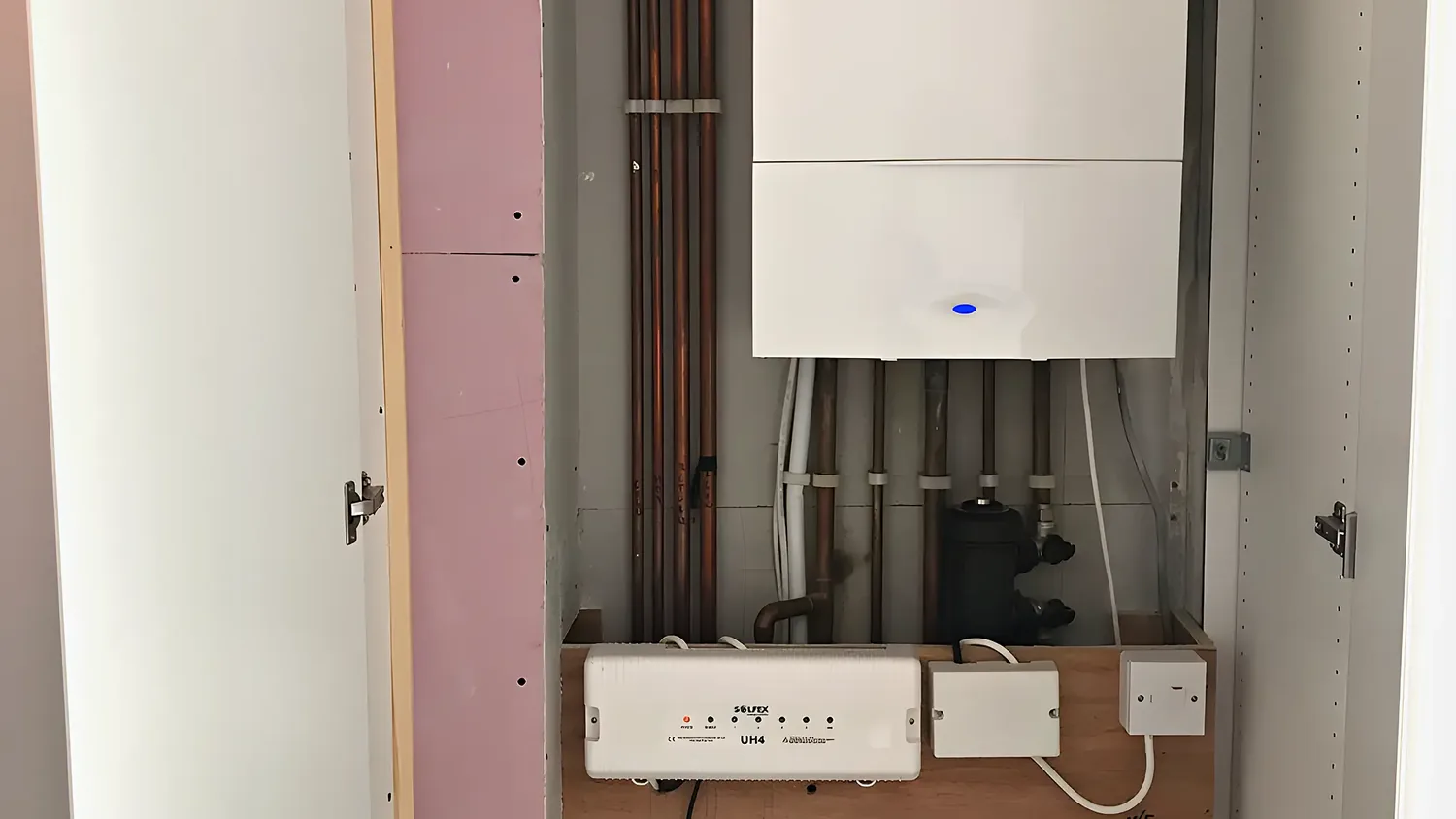 A new boiler in a built cupboard with the underfloor heating manifold below
