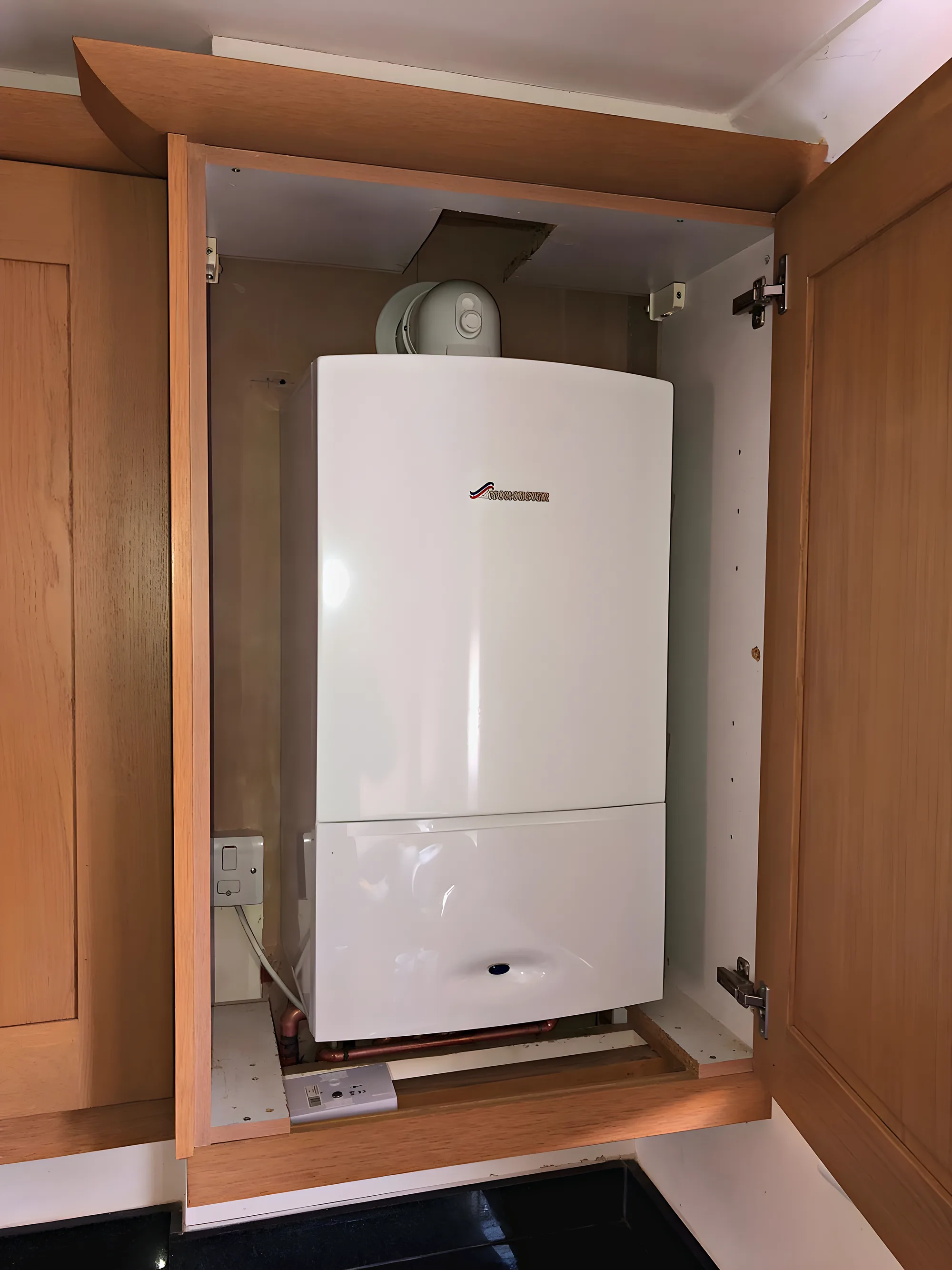 A new white combi boiler fitted neatly inside an oak kitchen cupboard