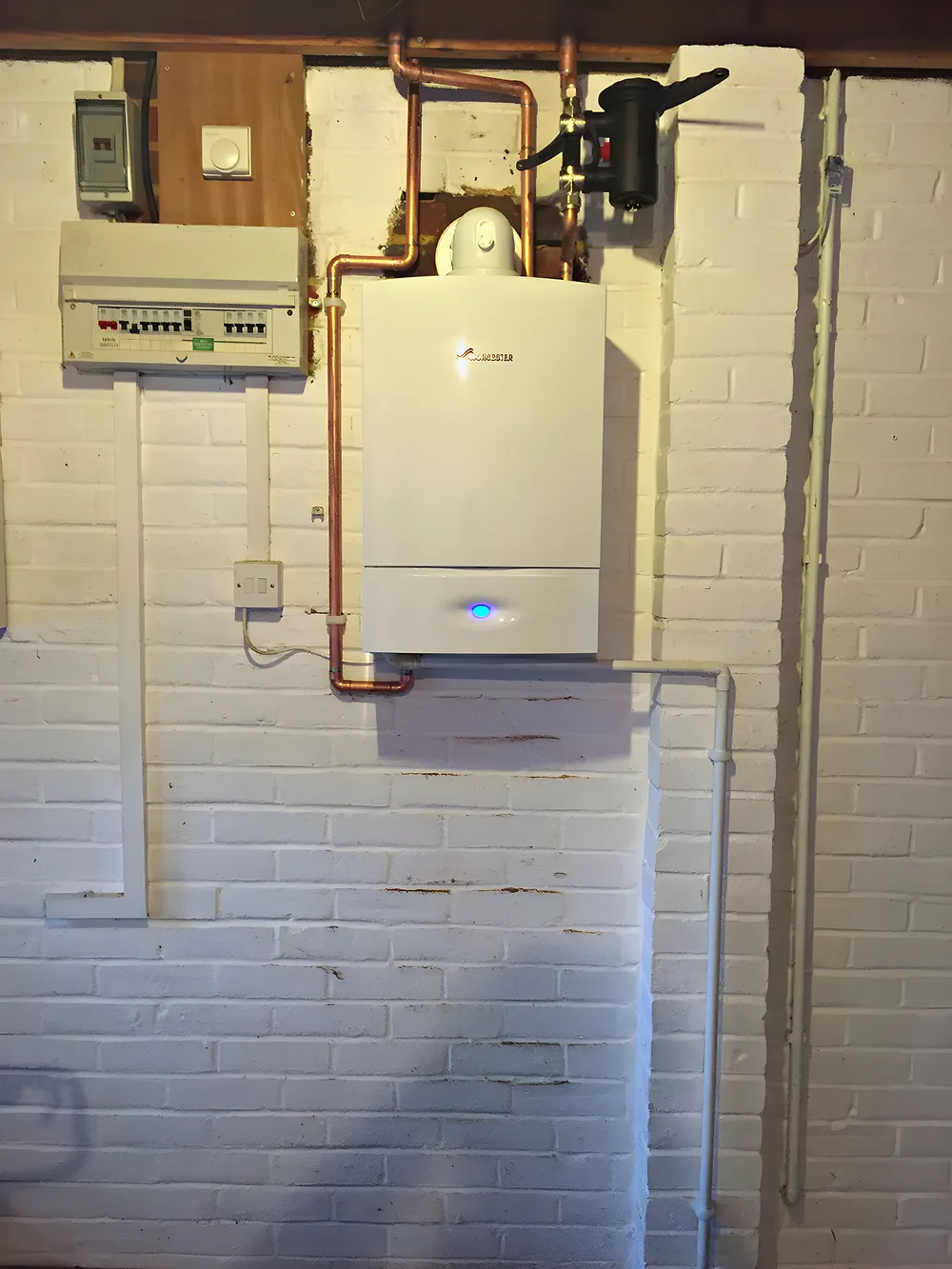 A boiler and controls fitted on a painted brick wall