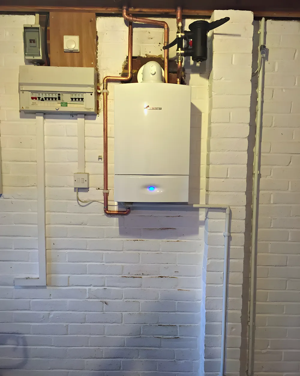 A boiler and controls fitted on a painted brick wall