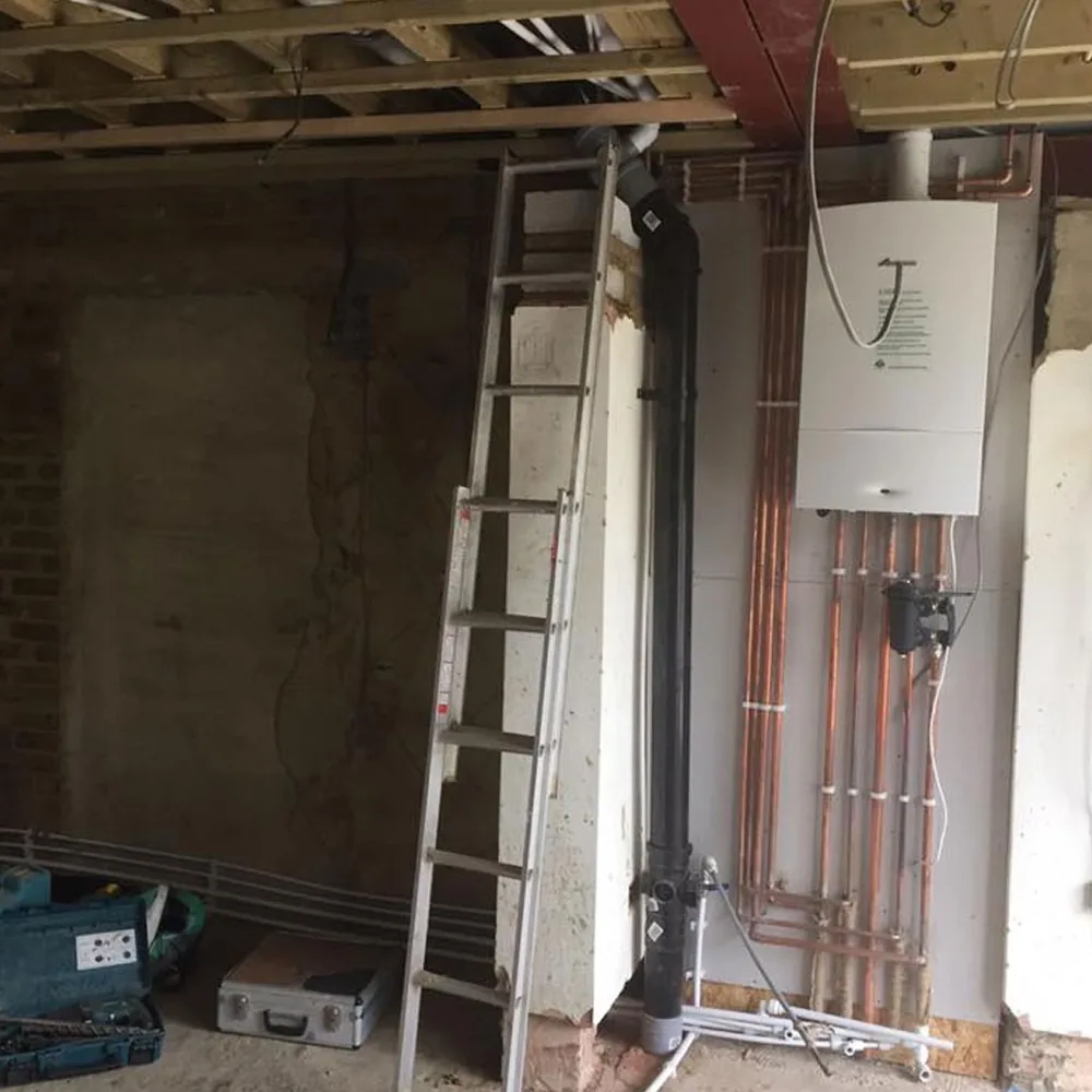 A boiler and new copper pipework fitted on a wall during a house renovation