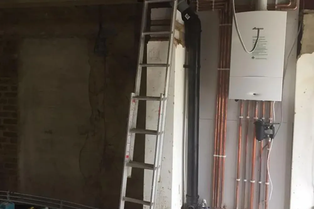 A boiler and new copper pipework fitted on a wall during a house renovation