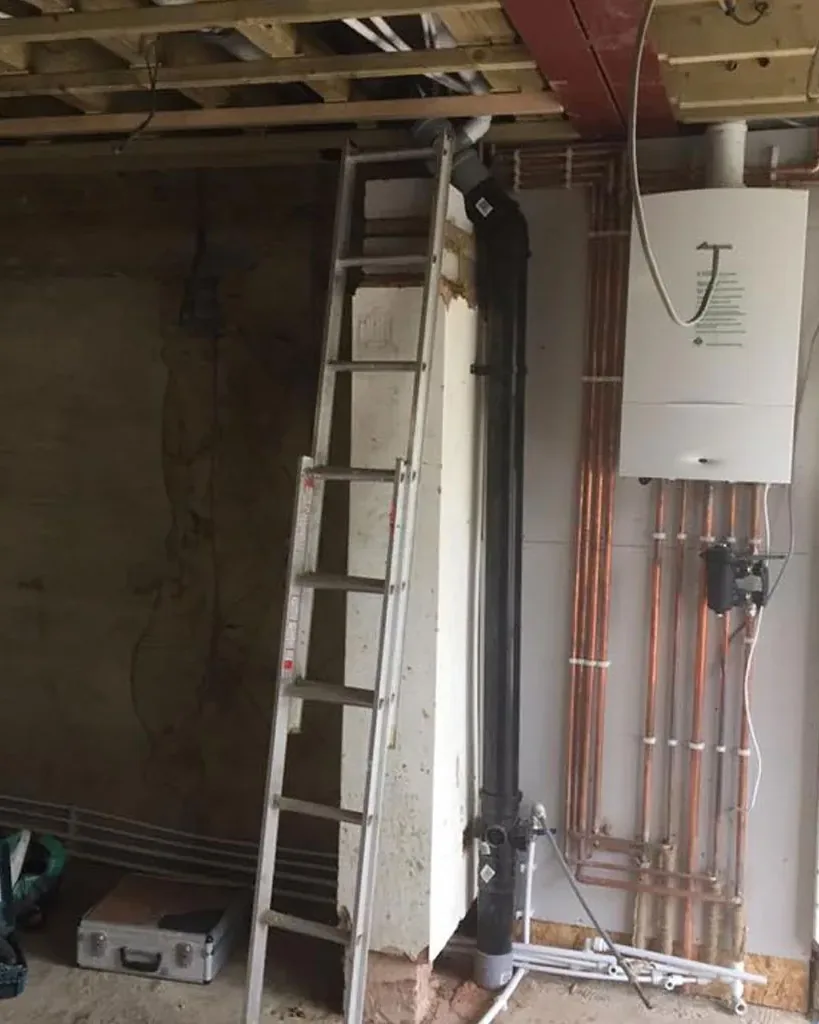 A boiler and new copper pipework fitted on a wall during a house renovation