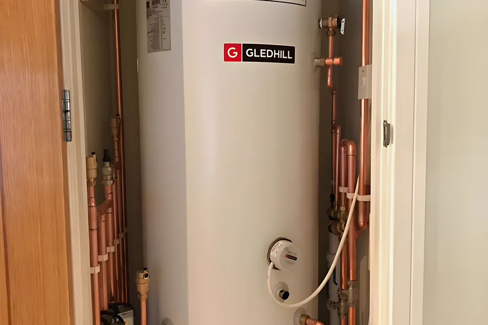A stainless unvented hot water cylinder in a cupboard with copper pipework