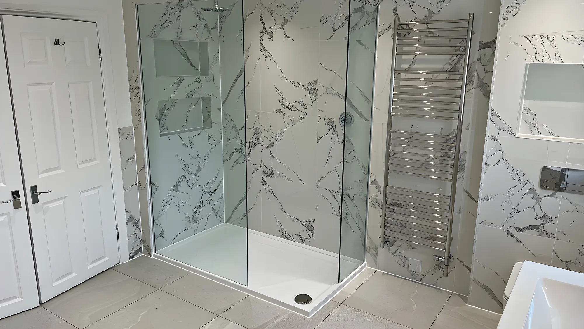 A marble effect walk in shower with a glass screen and a chrome ladder towel rail