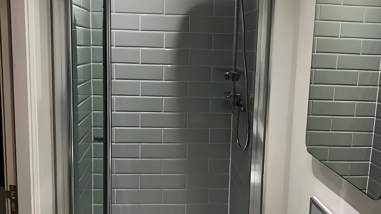 A shower enclosure lined with grey metro tiles